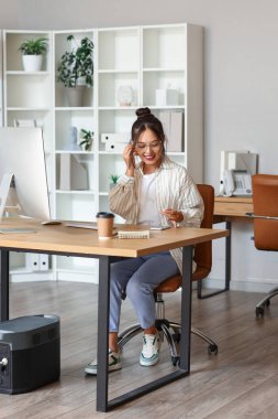 Ofisteki kulaklıklı genç Asyalı iş kadını.