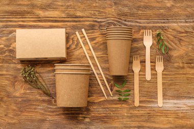 Kahverengi ahşap arka planda bitki dalları olan eko sofra takımı