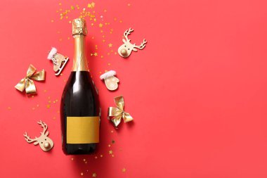 Noel süslemeleri ve kırmızı arka planda konfeti olan bir şişe şampanya.