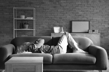 Depresyondaki olgun kadın evdeki kanepede yatıyor.