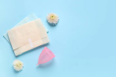 Mavi arka planda pedleri ve çiçekleri olan regl bardağı