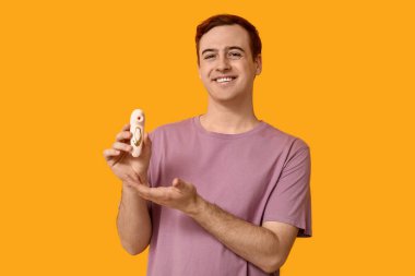 Sarı arka planda vibratörü olan yakışıklı bir genç.