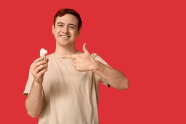 Kırmızı arka planda vibratöre bakan yakışıklı genç adam.