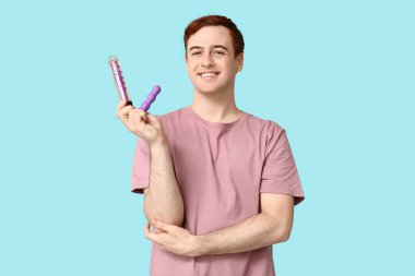 Mavi arka planda vibratörleri olan yakışıklı bir genç.