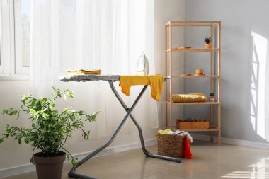 Ütü masası ve çamaşırları olan bir oda.