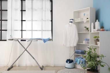 Ütü masası ve buharlı modern çamaşır odasının içi.