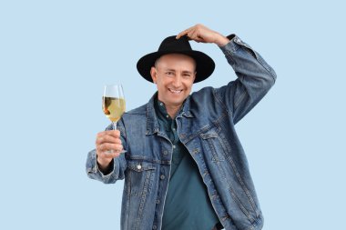 Mavi arka planda şarap kadehi olan olgun bir adam.