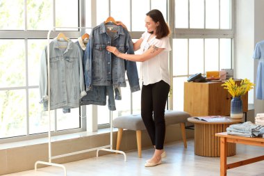 Giyim mağazasında kot ceketli kadın satıcı.