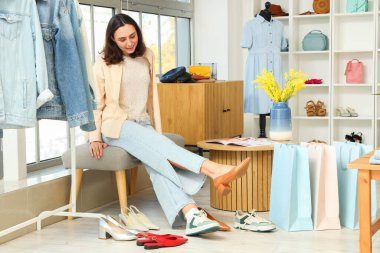 Genç bir kadın giyim mağazasında topuklu ayakkabı deniyor.