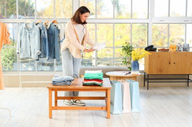 Mağazada katlanmış giysileri olan kadın satıcı.