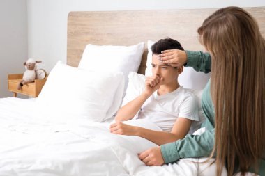 Anne hasta oğlunun alnına dokunuyor.