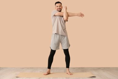 Yakışıklı adam bej duvarın yanında yoga yapıyor.