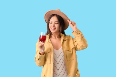 Mavi arka planda kırmızı şarap kadehi olan genç Asyalı kadın.