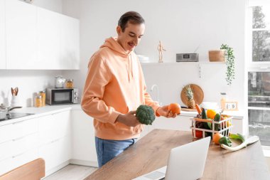 Mutfakta taze sebzeleri olan genç adam.