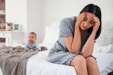 Yatak odasında doğum sonrası depresyon geçiren genç bir kadın.