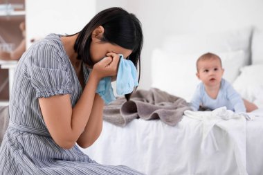 Çamaşırları yıkanmış, yatak odasında doğum sonrası depresyondan muzdarip genç bir kadın.