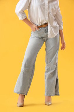 Sarı arka planda kotlu şık bir genç kadın.