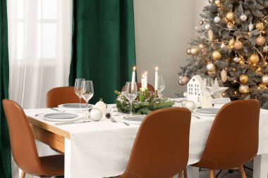 Zarif yemek odasında yanan mumlar ve Noel süslemeleri olan şenlik masası.
