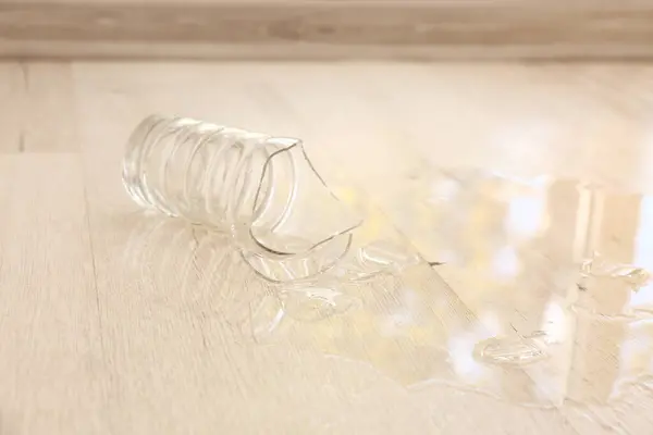 Wooden laminate floor with spilled water and shattered vase