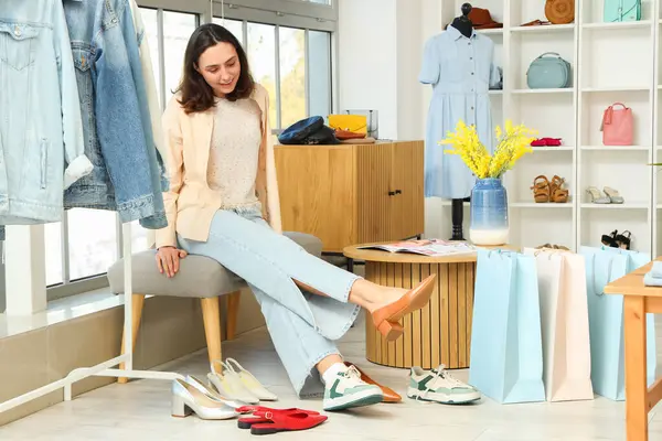 Genç bir kadın giyim mağazasında topuklu ayakkabı deniyor.