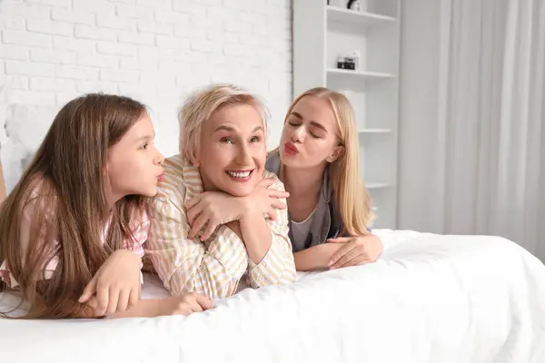 Little girl with her mom and grandmother lying in bedroom