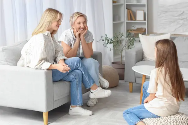 Little girl with her mom and grandmother talking at home