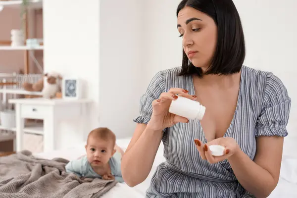 Doğum sonrası depresyon geçiren haplı genç bir kadın yatak odasında.