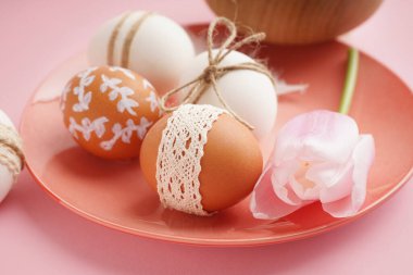 Pembe arka planda Paskalya yumurtası ve lale tabağı.