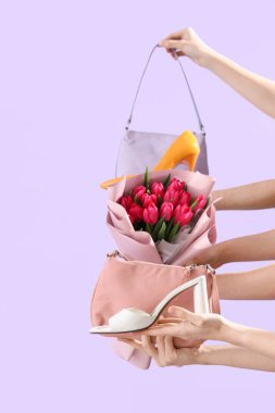 Yüksek topuklu ayakkabılar, el çantaları ve leylak arka planda bir buket lale. Uluslararası Kadınlar Günü için Alışveriş