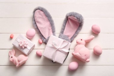 Paskalya yumurtalı tavşan kulakları ve beyaz ahşap arka planda hediye kutuları