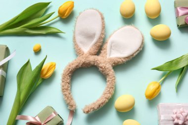 Paskalya yumurtalı tavşan kulakları ve turkuaz arka planda lale çiçekleri.