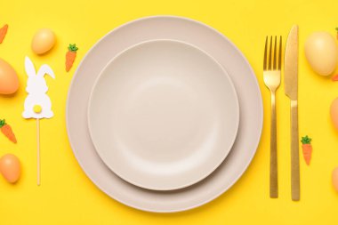 Güzel Paskalya sofrası. Sarı arka planda yumurtalar, oyuncaklar ve tavşanlarla servis ediliyor.