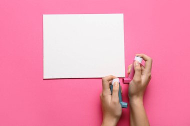 Astım spreyli çocuk elleri ve pembe arka planda boş bir kart.