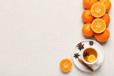 Sweet mandarins and cup of tea with star anise on white background