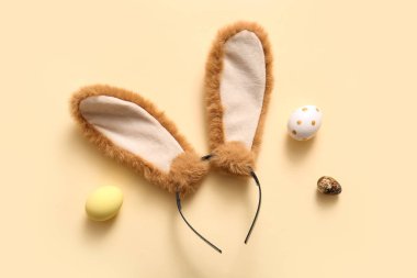Bej arka planda Paskalya yumurtası olan tavşan kulaklı.