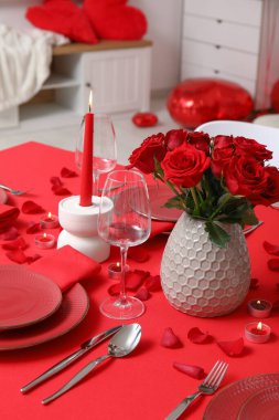 Sevgililer Günü için hazırlanmış şölen masası kırmızı güller ve evde yanan mumlarla süslenmiş.