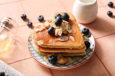 Kalp şeklinde lezzetli gözlemeler, bej kaplamalı yaban mersini ve fındıklı fındıklar, yakın plan. Sevgililer Günü kutlaması