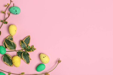 Pembe arka planda yaprakları olan Paskalya yumurtaları