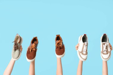 Mavi arka planda farklı şık spor ayakkabıları olan kadın elleri. Ayakkabı tamiri kavramı