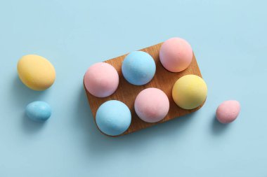 Mavi arka planda boyanmış Paskalya yumurtaları olan tahta tutucu.