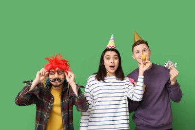 Yeşil arka planda kağıt balığıyla kılık değiştirmiş genç şok olmuş arkadaşlar. 1 Nisan kutlamaları