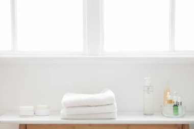 Banyodaki masasında temiz havlular olan cilt bakımı ürünleri.