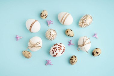 Mavi arka planda süslü Paskalya yumurtaları ve mor çiçekler.