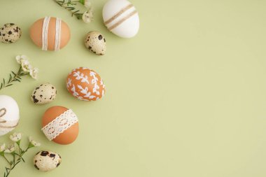 Süslü Paskalya yumurtaları ve yeşil arka planda küçük çiçekler.