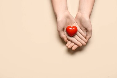 Bej arka planda kırmızı kalpli kadın elleri