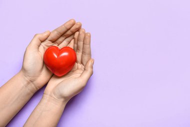 Leylak arkaplanda kırmızı kalpli bir kadın eli.