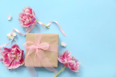 Güzellik paketlenmiş hediye kutusu ve cyan arka planda çiçekler