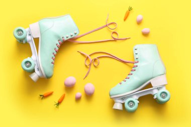 Sarı arka planda havuçlu klasik patenler ve Paskalya yumurtaları.