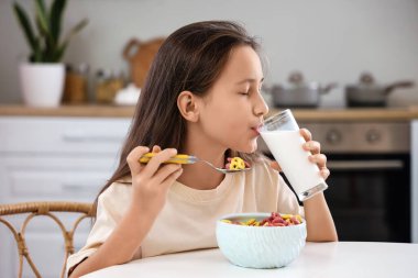 Evde sütle mısır gevreği yiyen tatlı küçük kız.