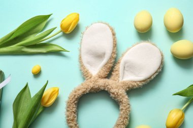 Paskalya yumurtalı tavşan kulakları ve turkuaz arka planda lale çiçekleri.